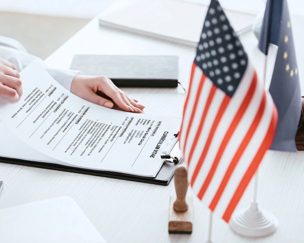 CV on the desk at the US embassy next to the American flag during the J1 visa interview